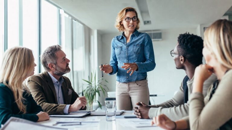 Professionelles Business-Beitragsbild: Zwei junge Consultants diskutieren vor einer digitalen Tafel, die Geschäftsprozesse und KI-Symbole zeigt